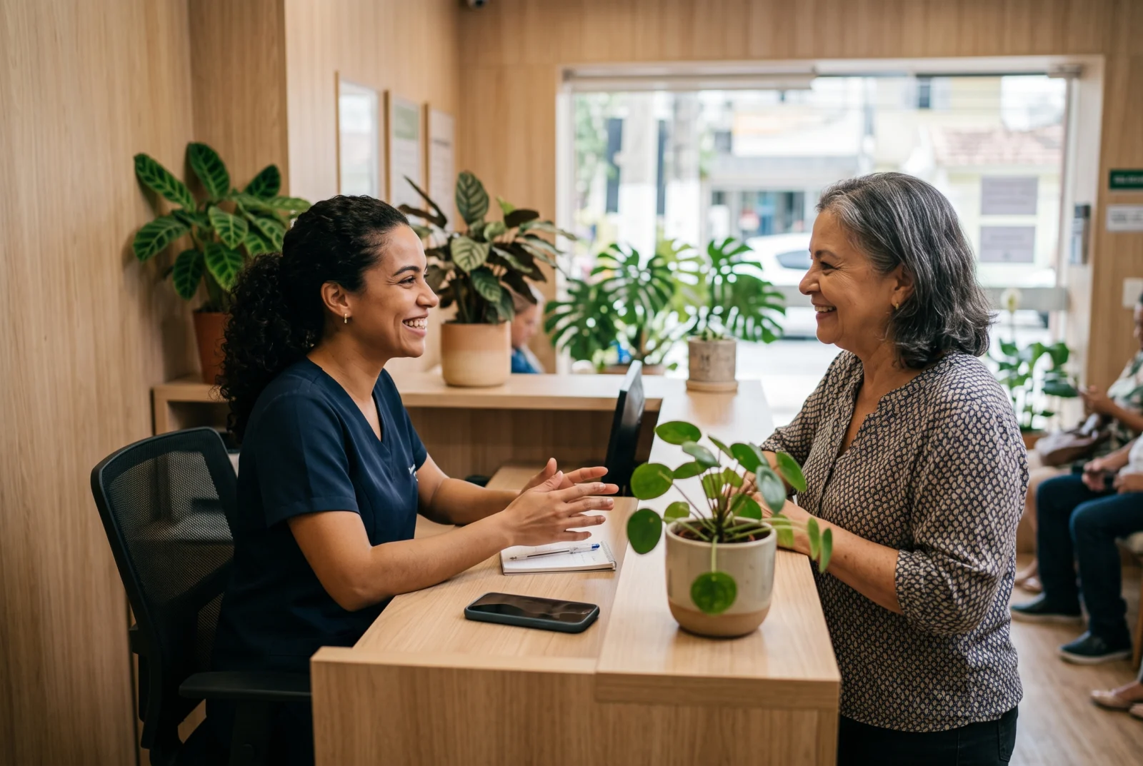 Recepcionista de clínica sorrindo enquanto atende uma paciente no balcão